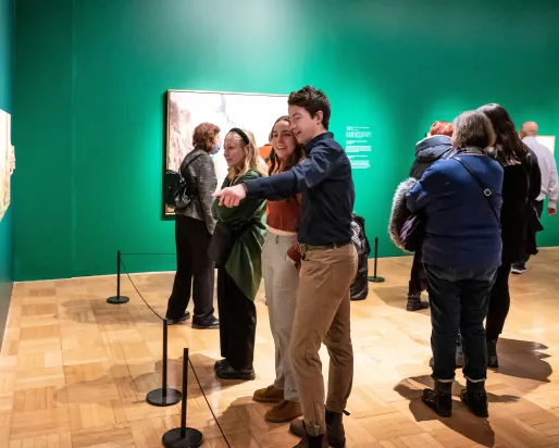 Memebr Preview—Kent Monkman: Being Legendary A young couple smile whiling looking at a picture the man is pointing at.