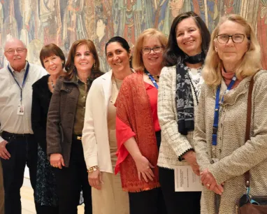 A diverse group of people poses in front of a colorful mural, showcasing their smiles and the vibrant artwork behind them. A diverse group of people poses in front of a colorful mural, showcasing their smiles and the vibrant artwork behind them.