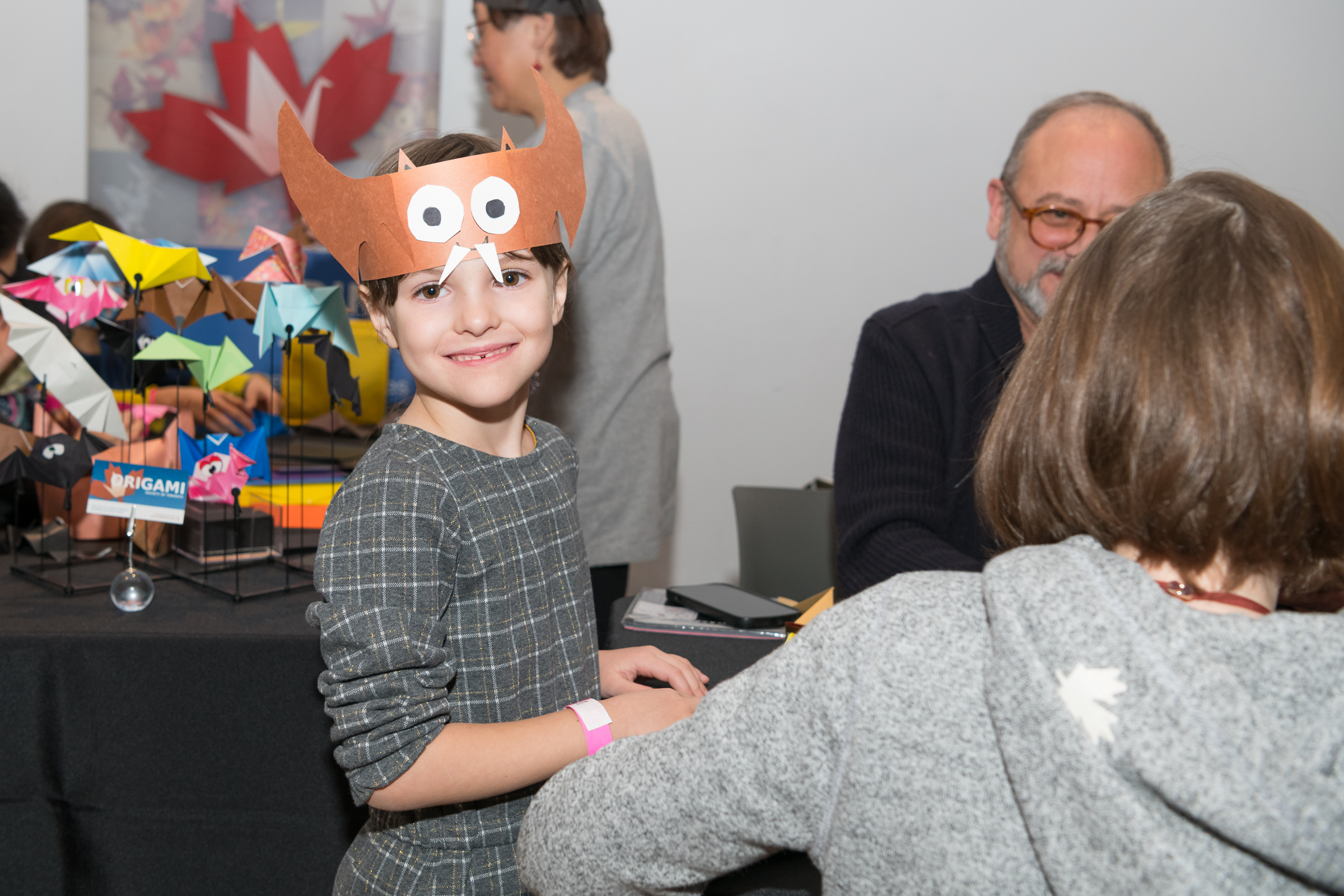 A girl smiles showing off the bat hat she has made with craft paper.