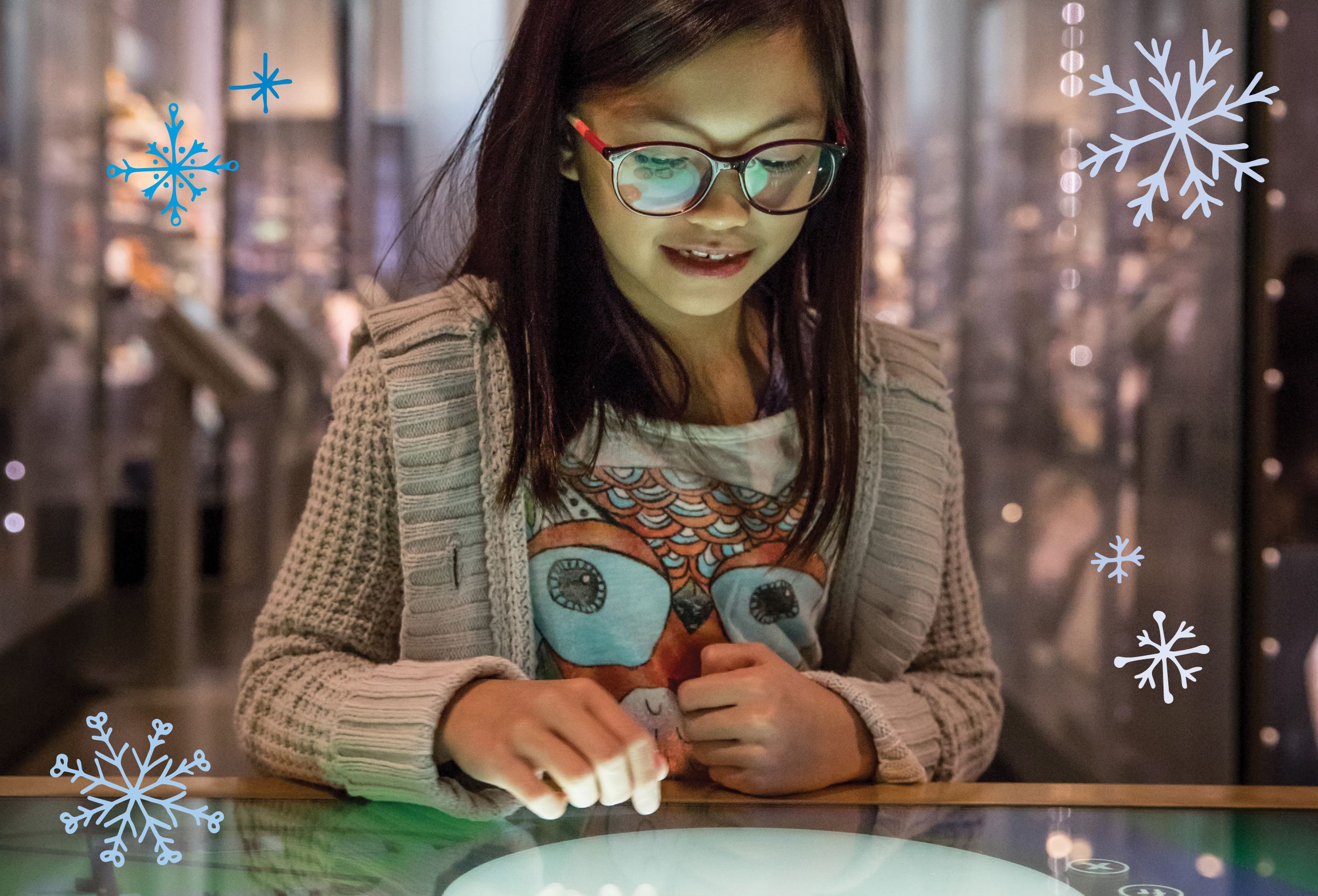 A girl stares down and smiles in wonder as she interacts with a screen in the Museum.