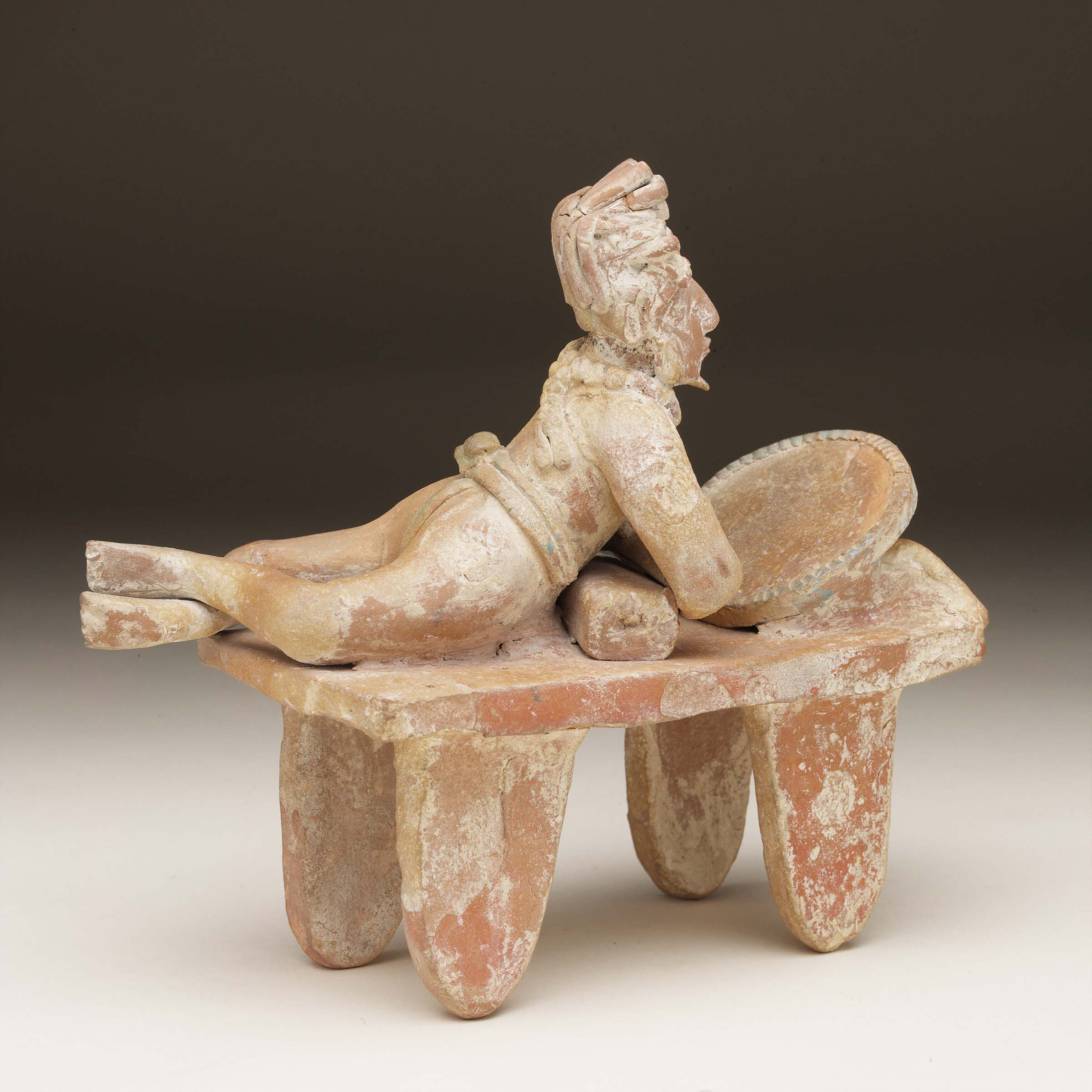 Clay statue of a reclining noble looking into a mirror.