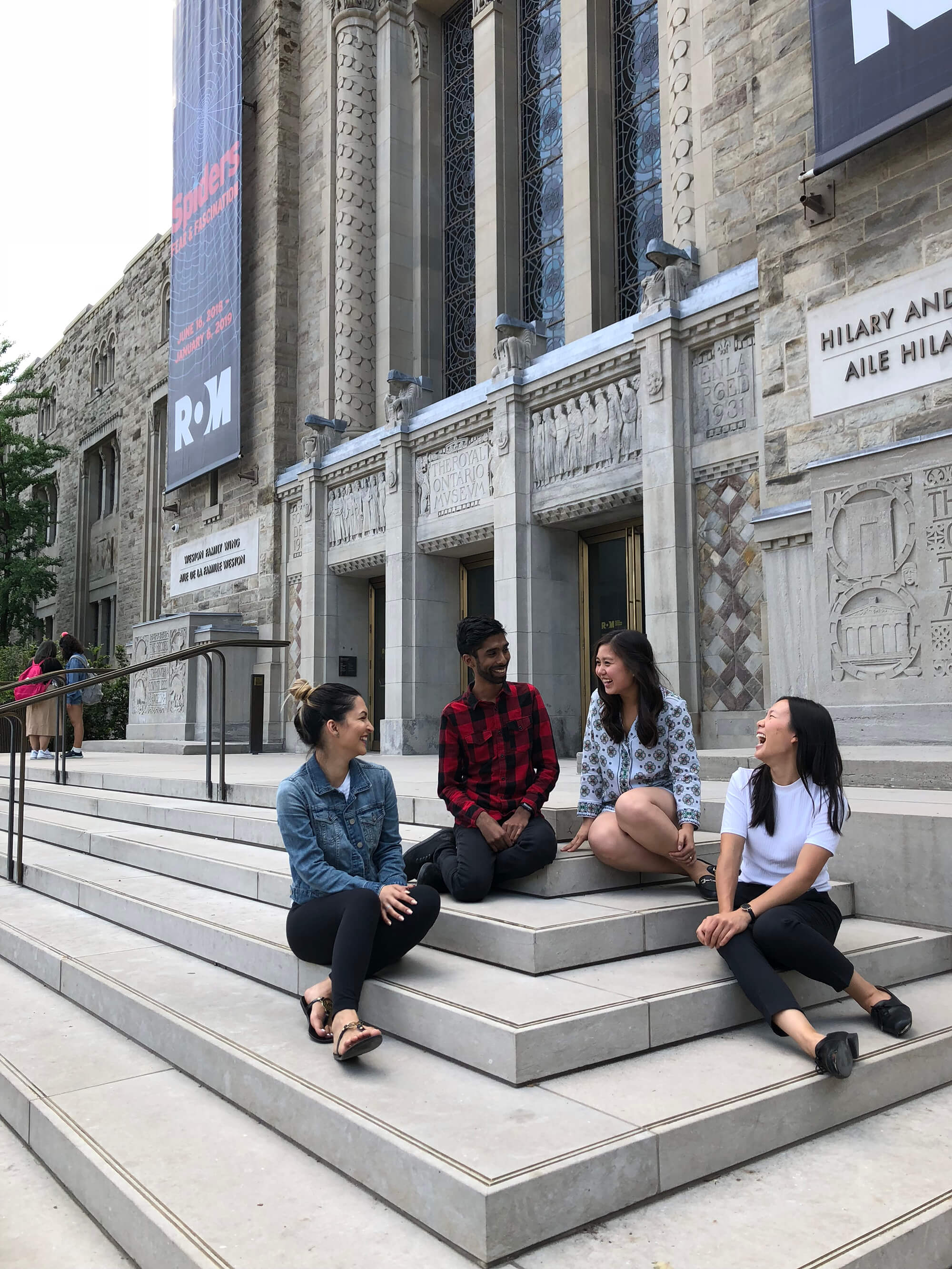 Bryan Hansraj sitting on the front steps of the ROM with a small group of people.