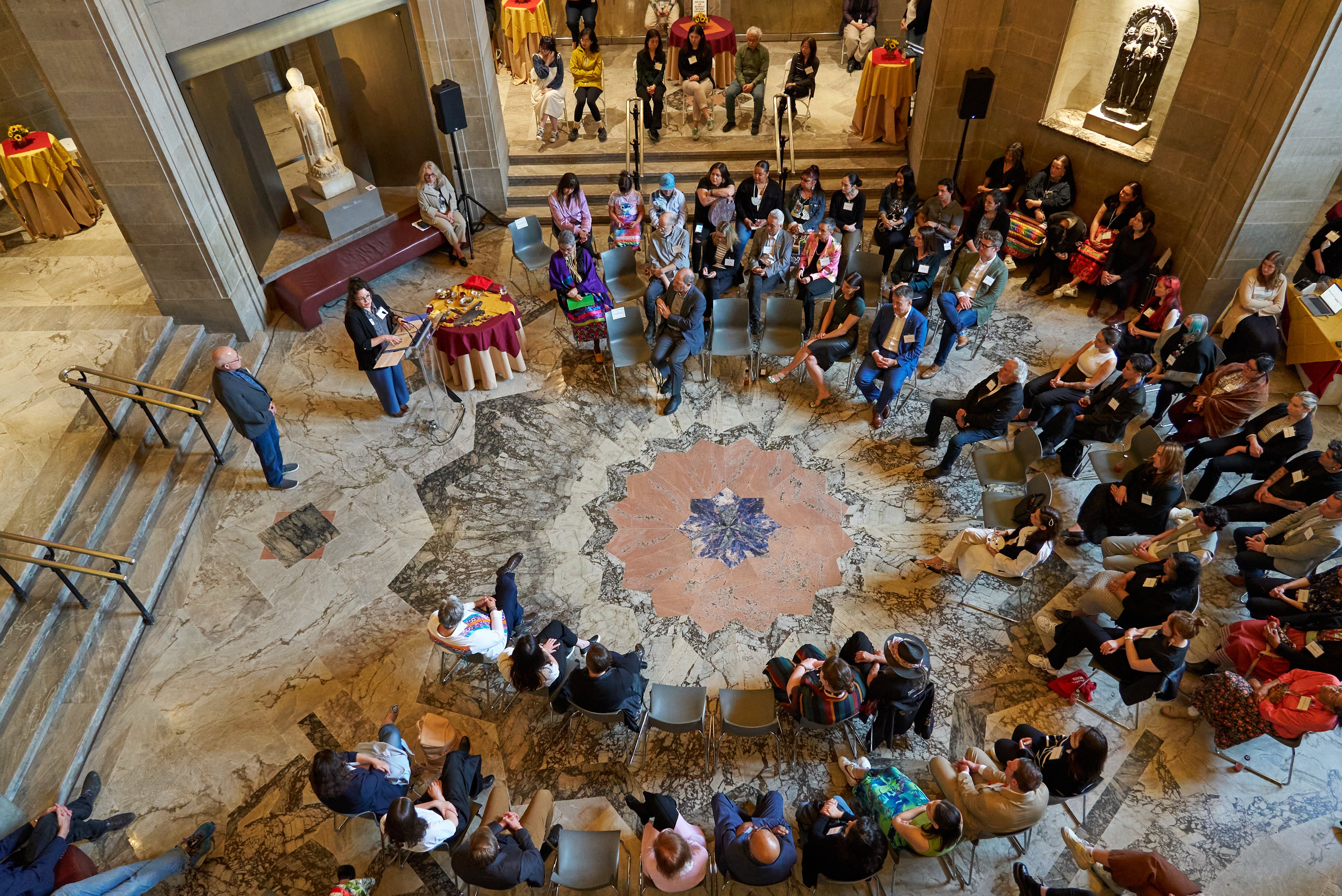 Presentation attendees in a large circle listening to a presentation.