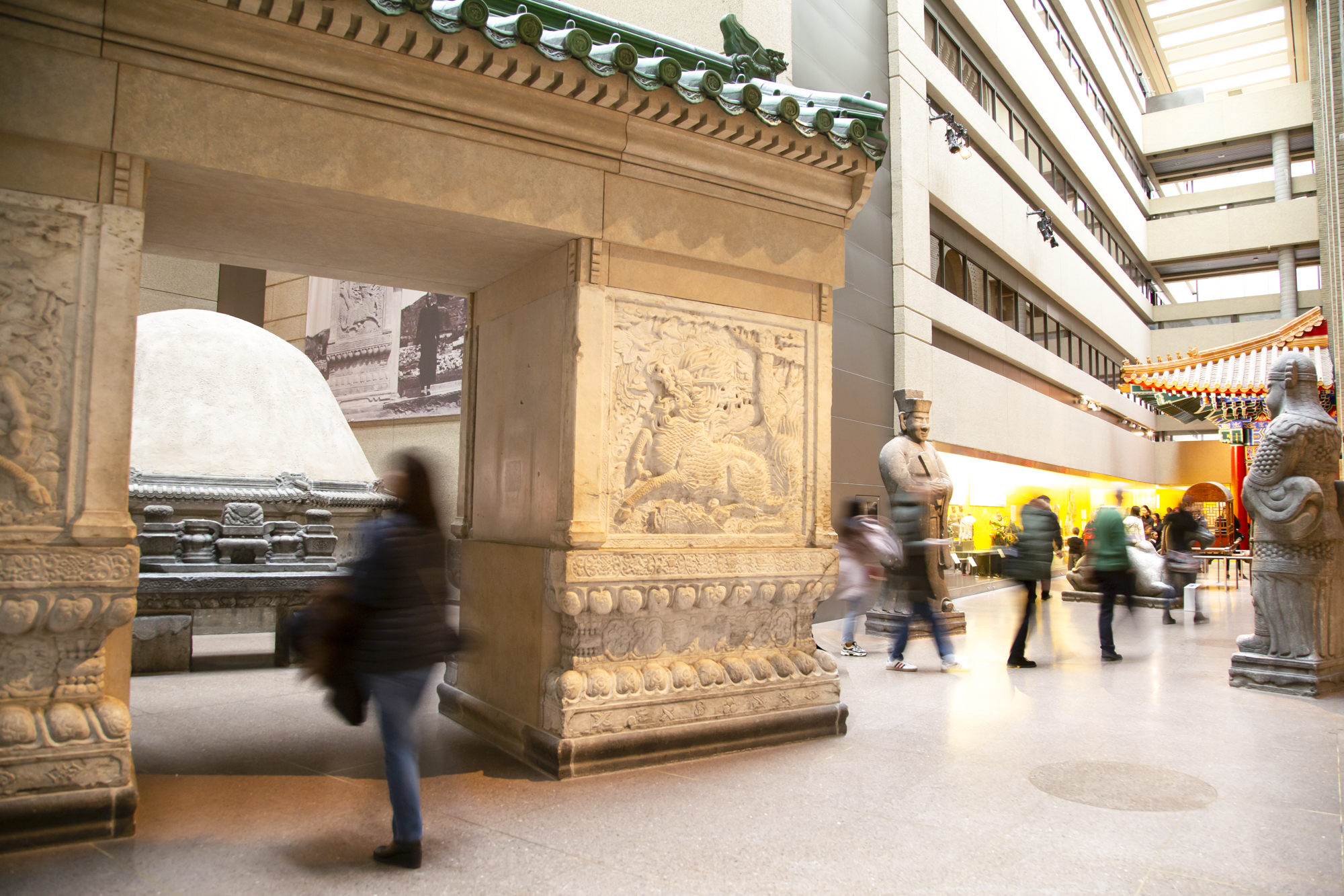 People walk through a gallery with a large entry gate