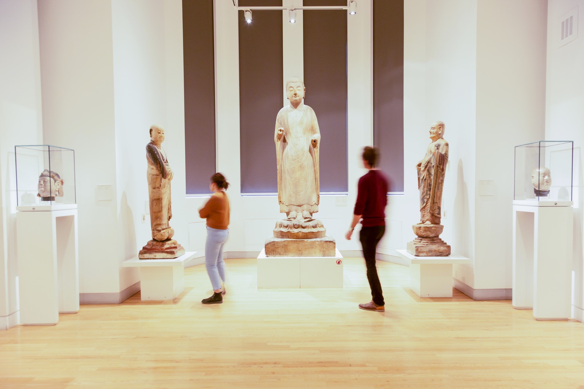 Two people look at three large Chinese sculptures.