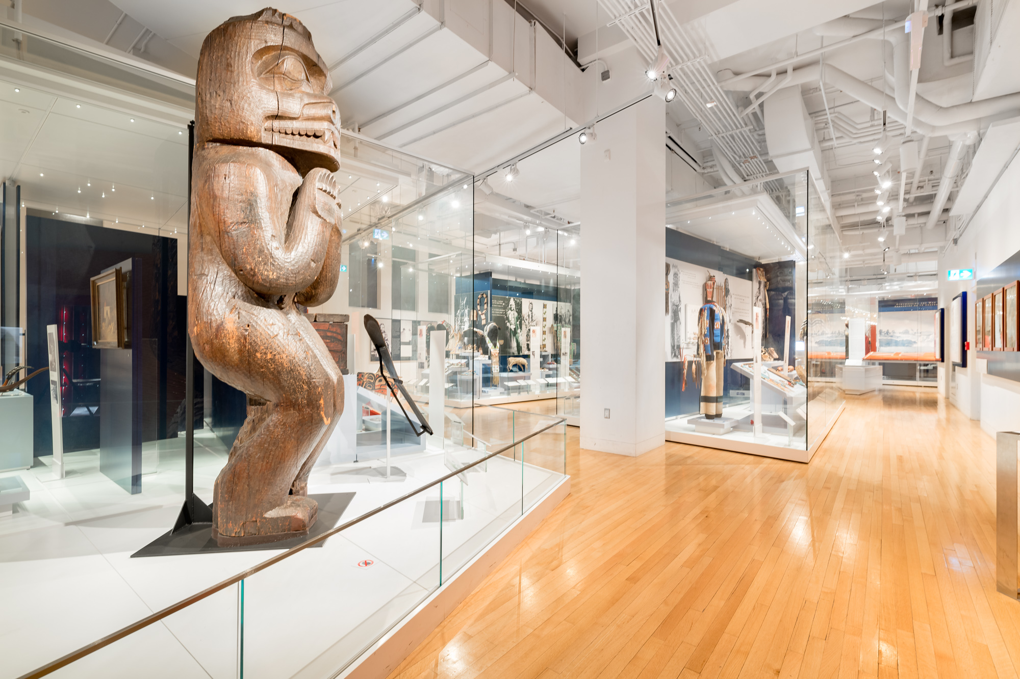 Une galerie avec, au premier plan, un grand poteau de maison en bois sculpté