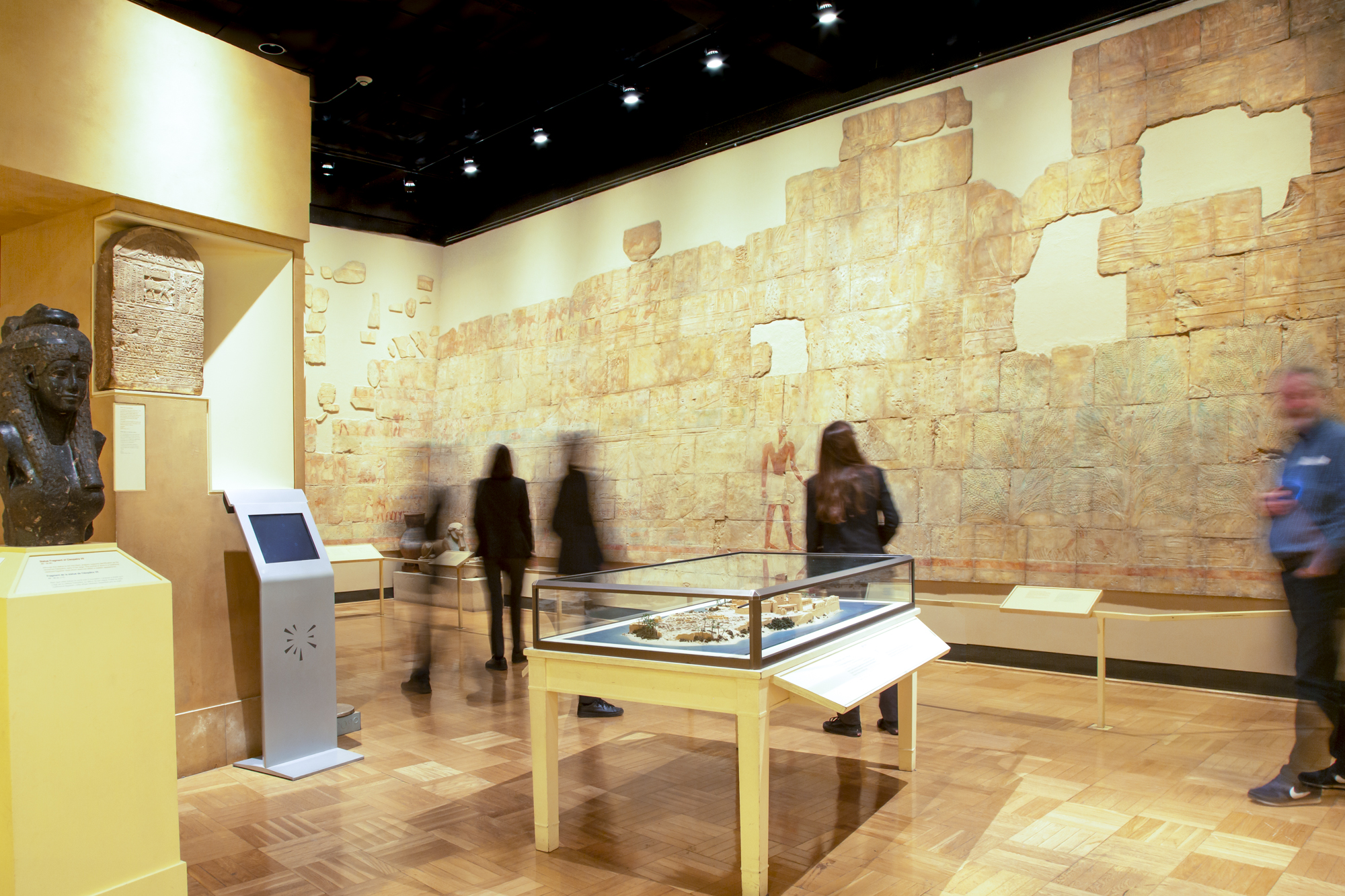 Les gens regardent le mur de la galerie qui présente une reconstruction d'un mur égyptien peint.