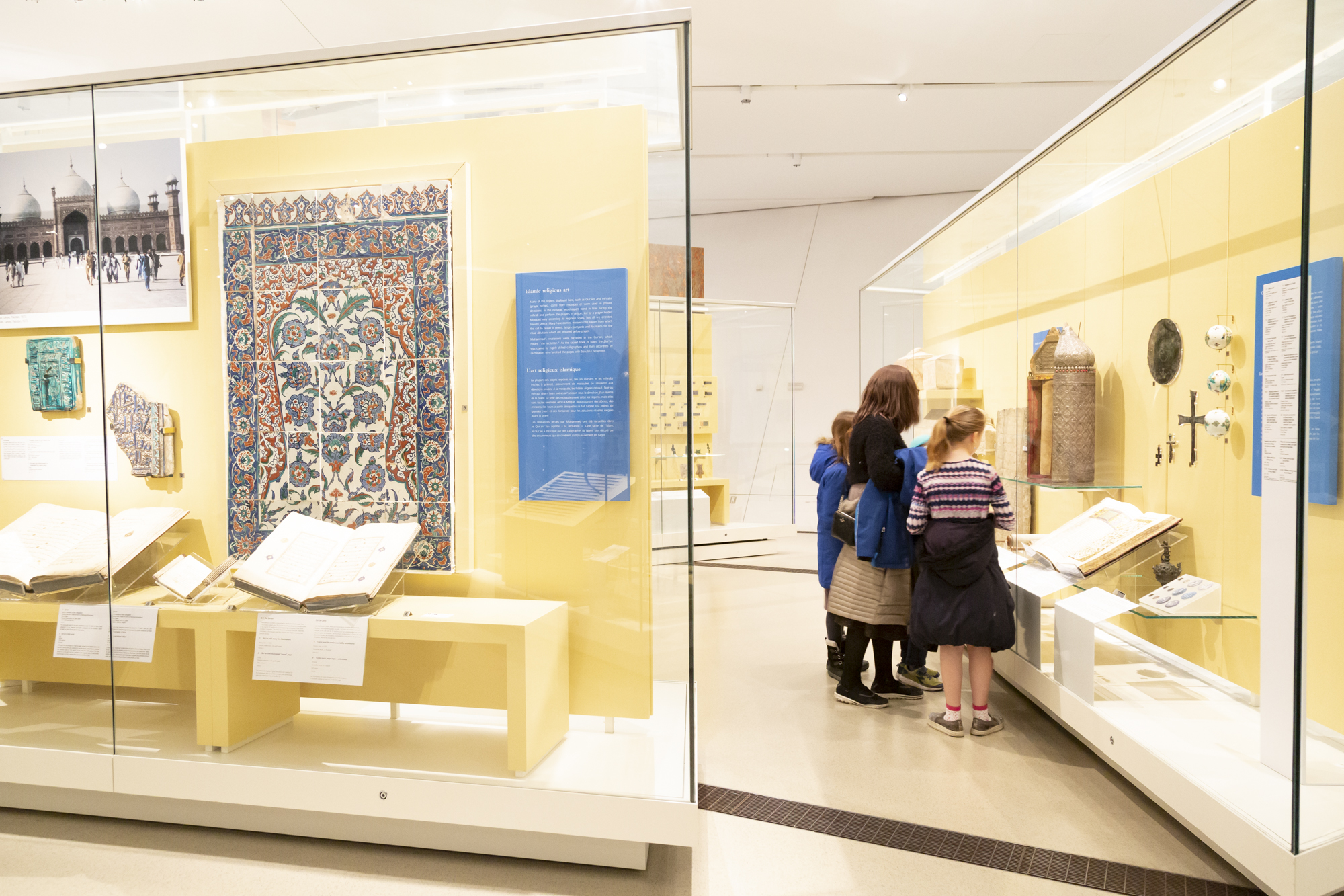 A family examines a Middle Eastern artifact in a gallery case.