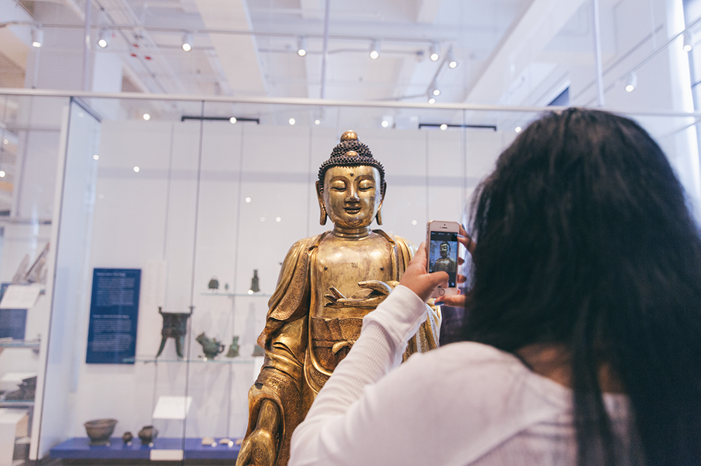 Person taking photo of statue in ROM gallery