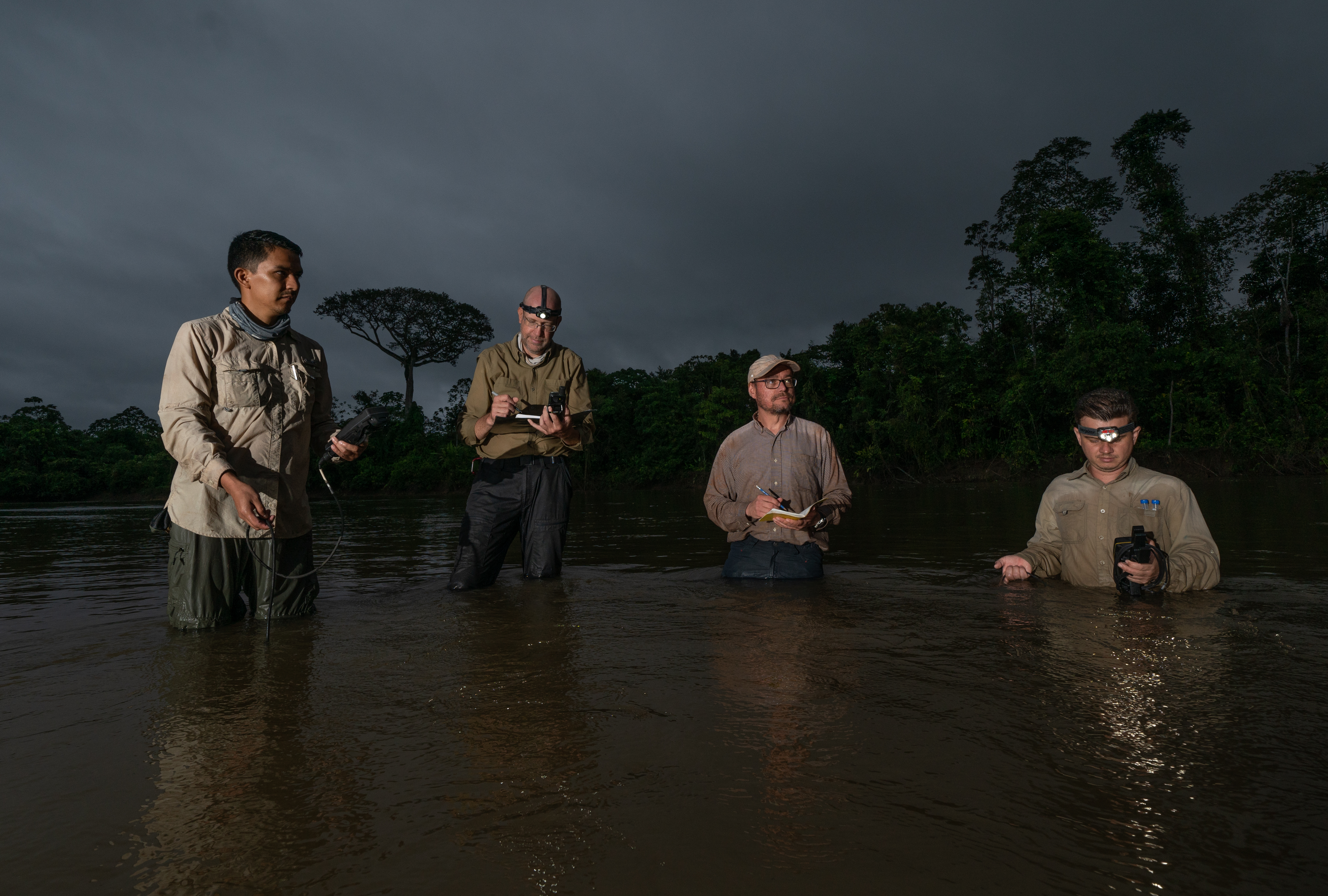 Four people standing knee-deep in water with equipment collecting data