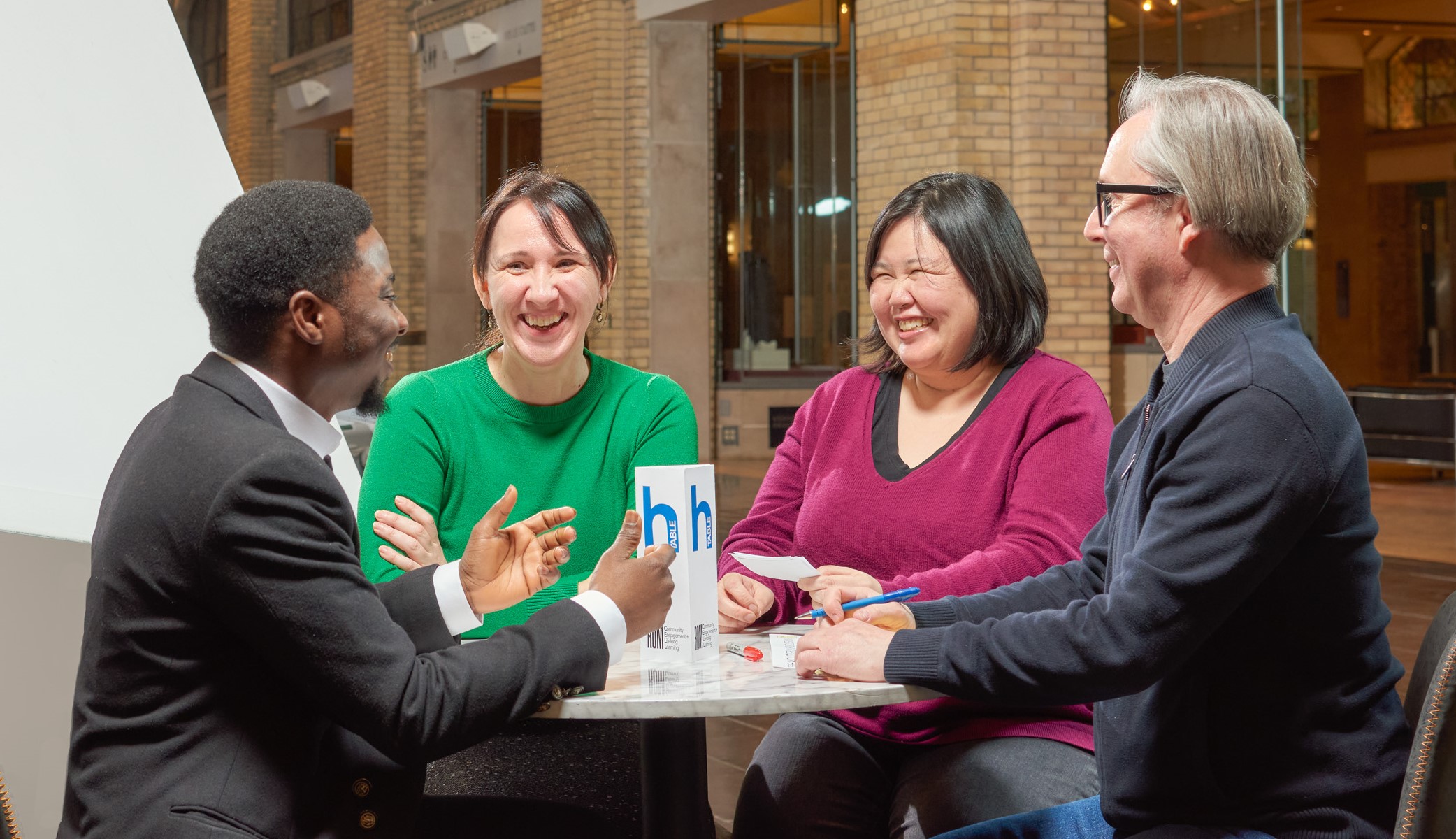 Four people stand around a table happily chatting