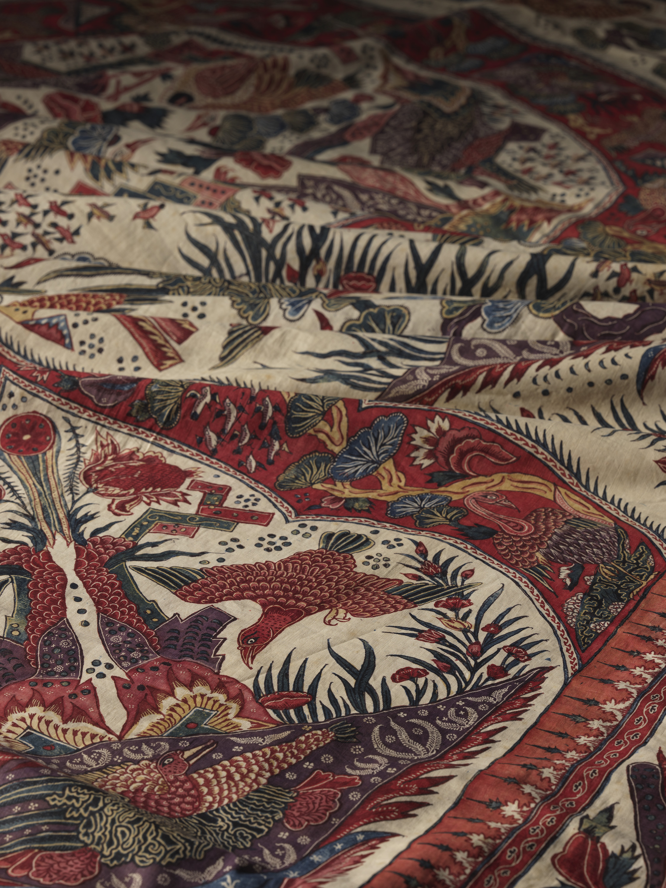  A close-up of red and black fabric featuring an intricate bird design, showcasing vibrant colors and detailed patterns.