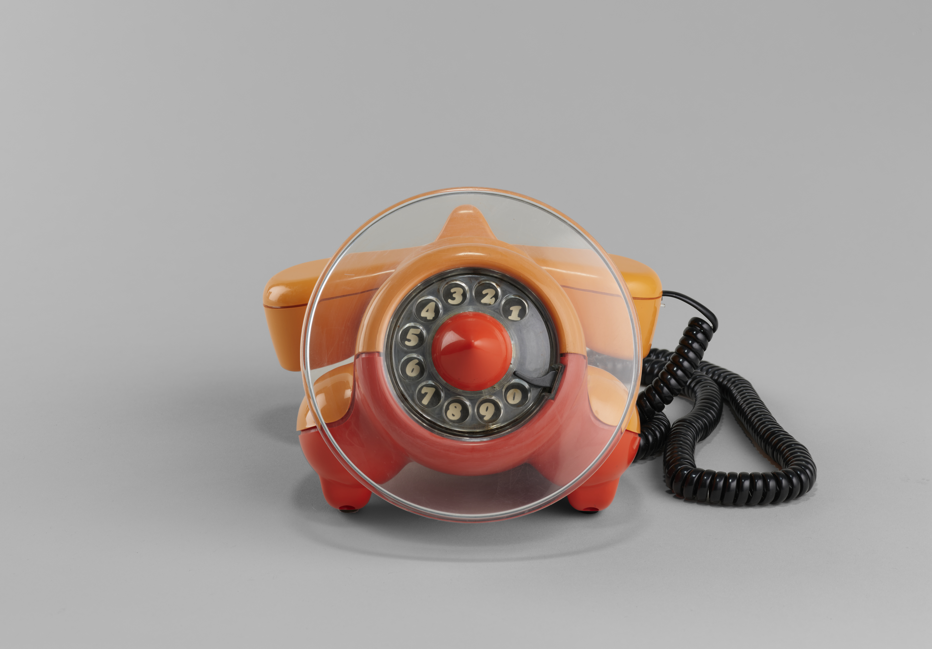 An orange and red corded telephone resting on a surface, showcasing its vibrant colors and classic design.