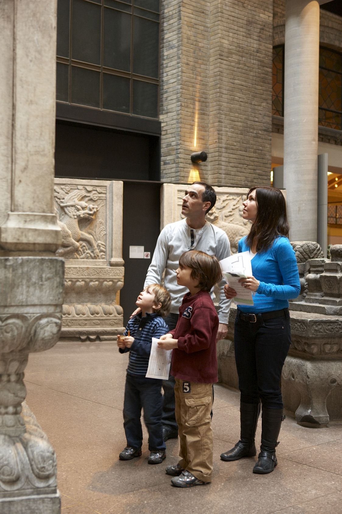 Family of four holding papers and examining an object at the Museum