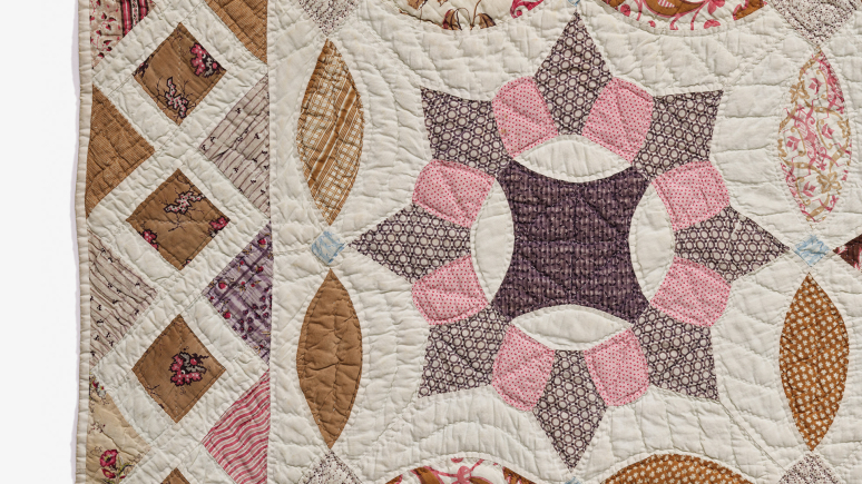 A close-up view of a quilt featuring an intricate design in shades of pink and brown.