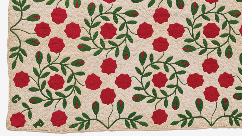 A beautifully crafted red rose quilt adorned with intricate green leaves, showcasing vibrant colors and elegant design.