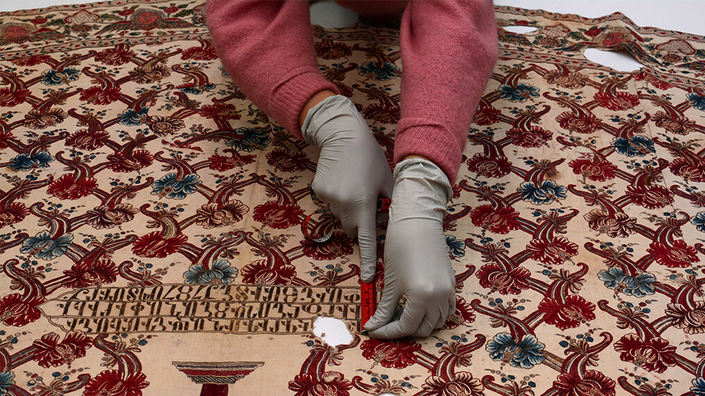 A person wearing medical gloves takes measurements on the surface of the cope.
