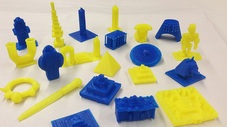 Twenty one blue and yellow 3D printed objects that include pyramids and obelisks
