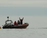 From the Great Whales, curator conversations, Zodiac boat on the ocean with researchers looking toward the photographer.