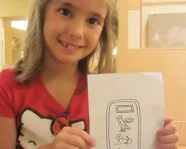 A girl holds a drawing of Egyptian Heiroglyphs
