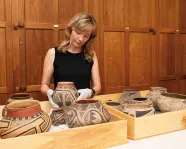 Museum technician in a collections room with artifacts.