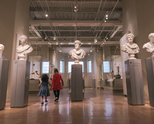 two people walking through the Roman portrait display in the Gallery of Rome.