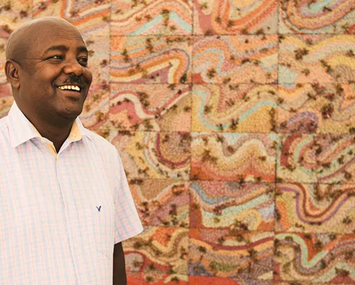 Elias Sime standing in front of his artwork.