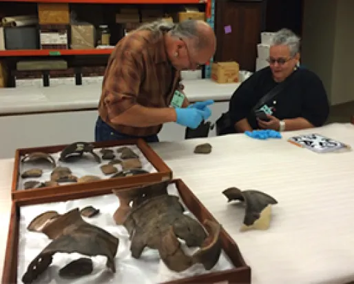 Two archaeologists examining objects.
