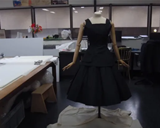 Screenshot of a video of a black sleeveless dress on a mannequin in a research lab.
