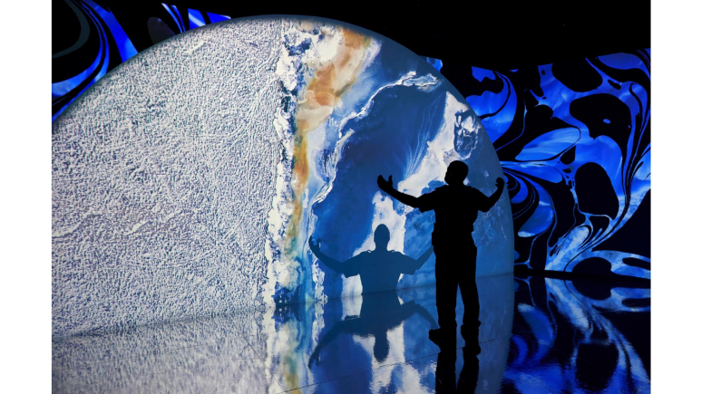 man standing in front of blue earth sphere with arms out