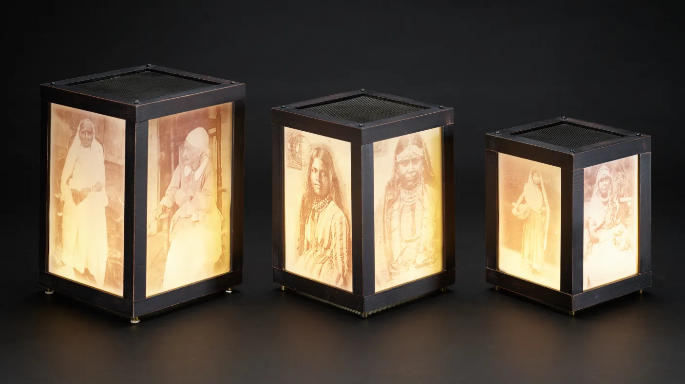 Three illuminated rectangular lanterns with images on the glass.