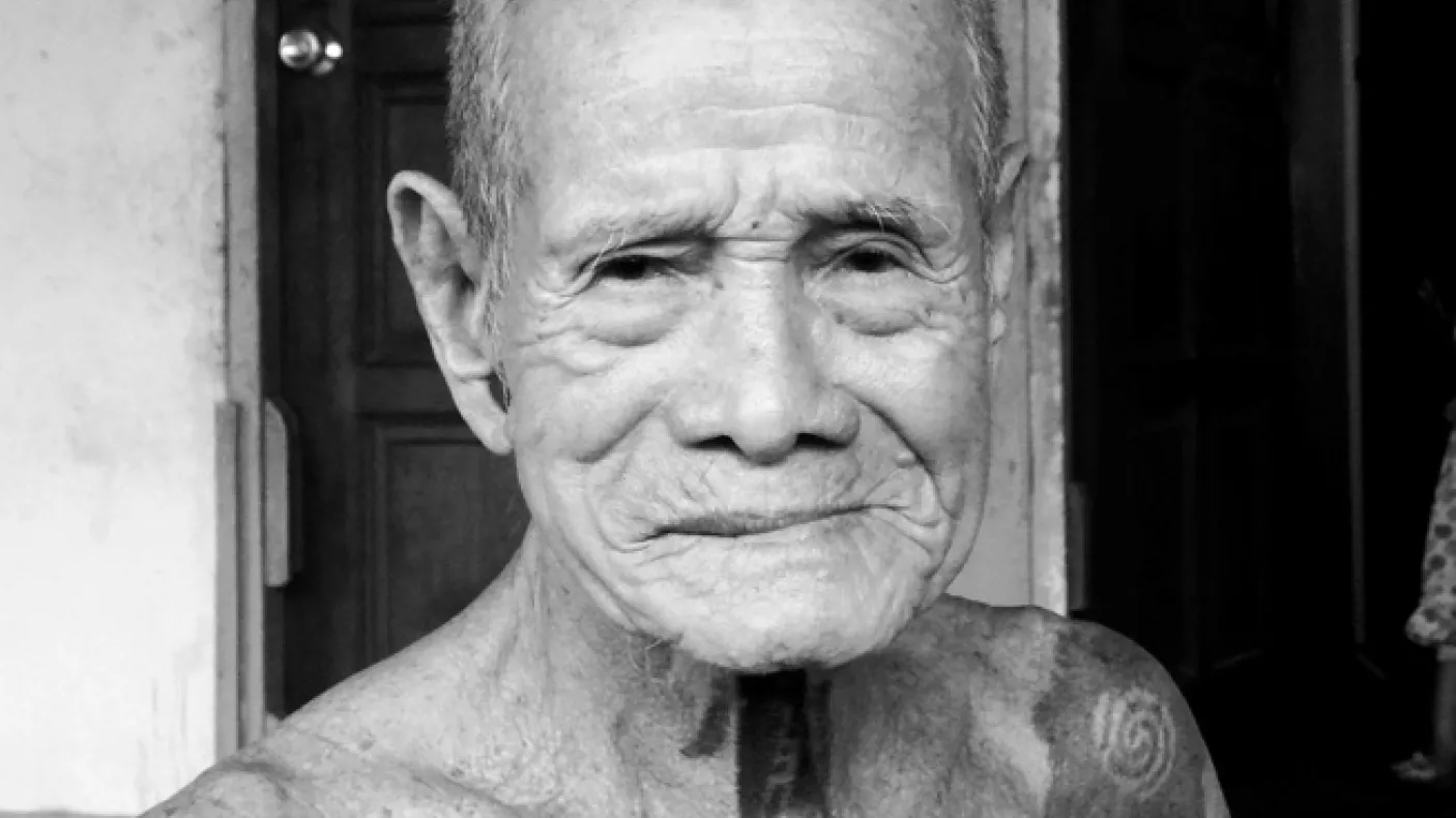 An Iban elder at Nanga Beretik longhouse.
 Black and white photograph of an older man with tattoos on his neck and shoulders