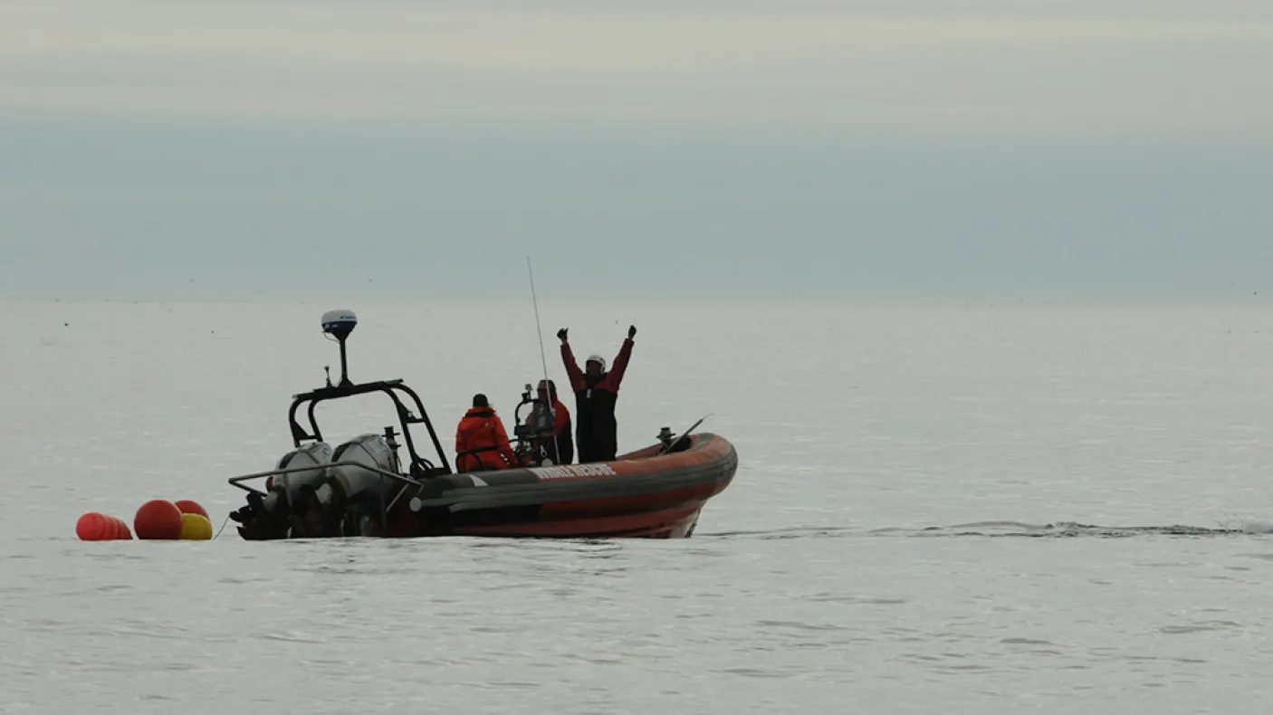 From the Great Whales, curator conversations, Zodiac boat on the ocean with researchers looking toward the photographer.