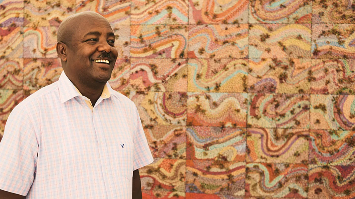 Elias Sime standing in front of his artwork.