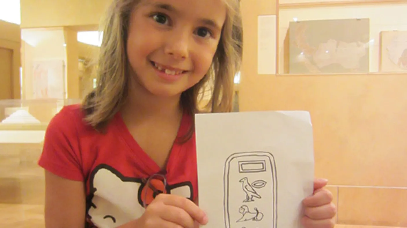 A girl holds a drawing of Egyptian Heiroglyphs
