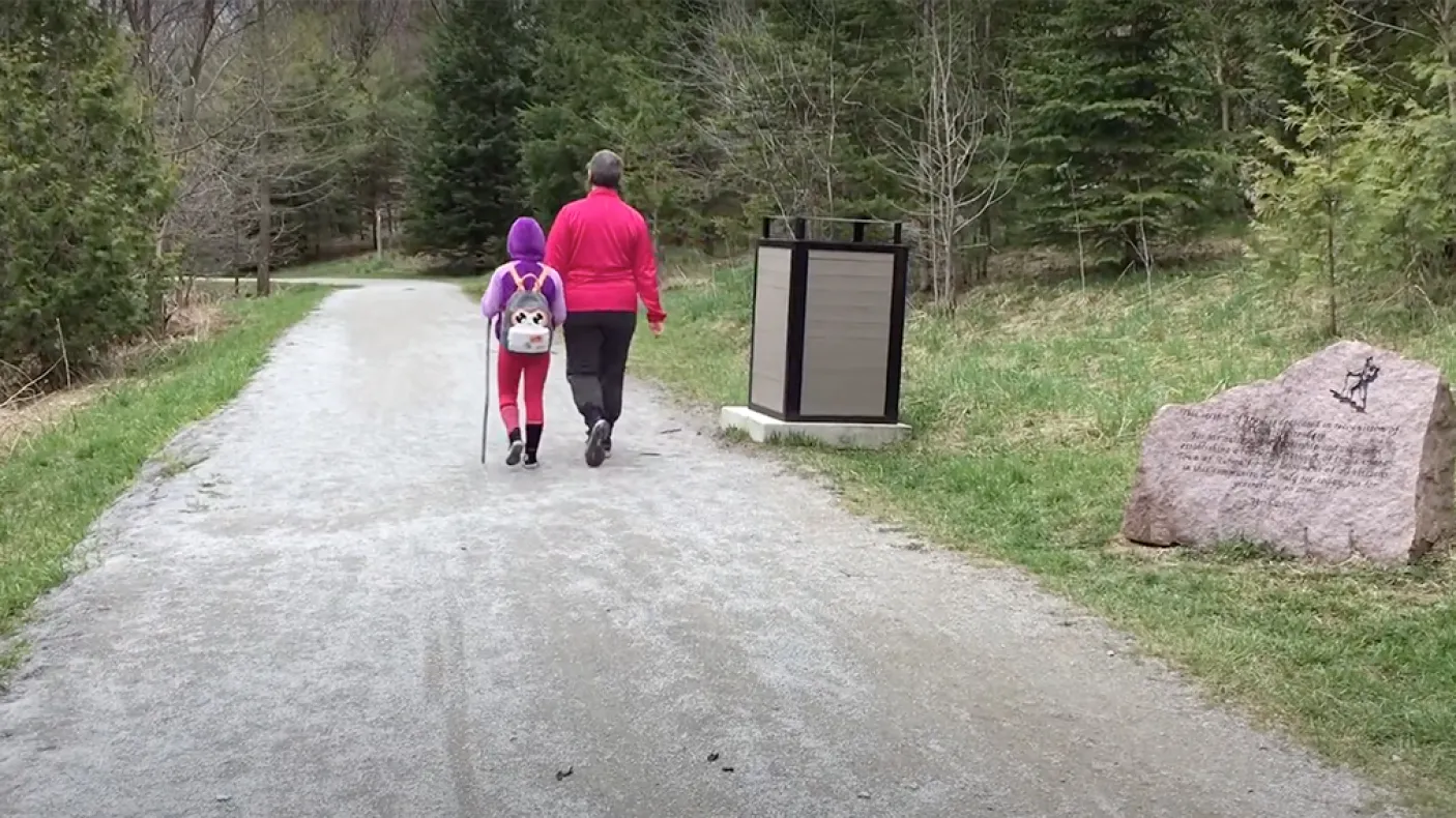 Femme et enfant marchant le long d'un sentier dans une forêt.
