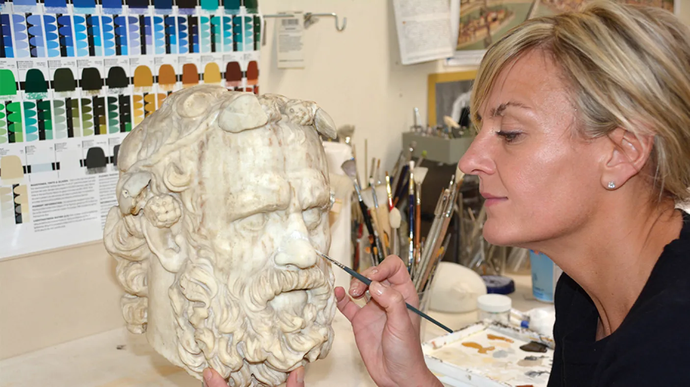 Laura Lipcei painting a Greek statue.