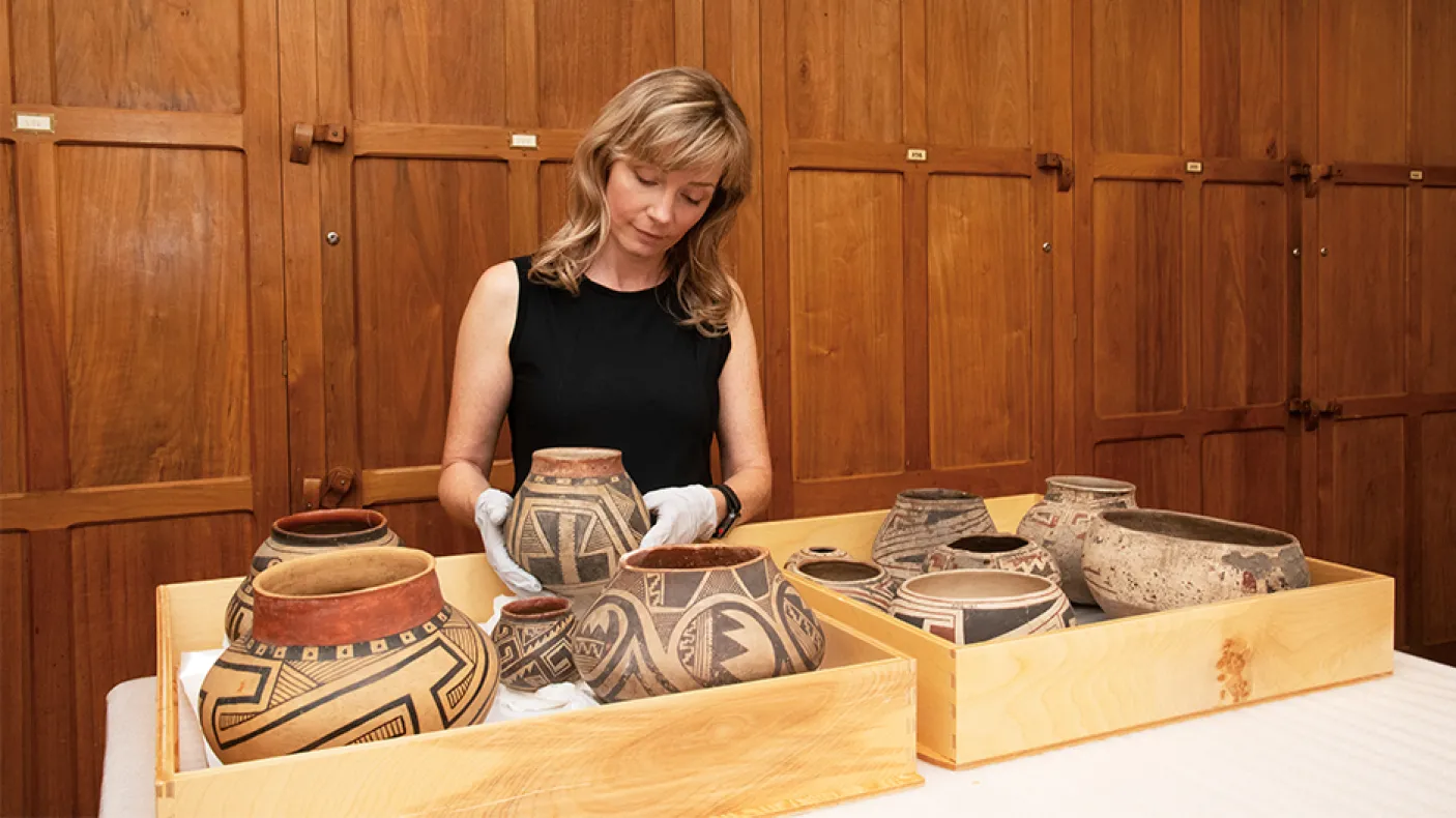 Museum technician in a collections room with artifacts.