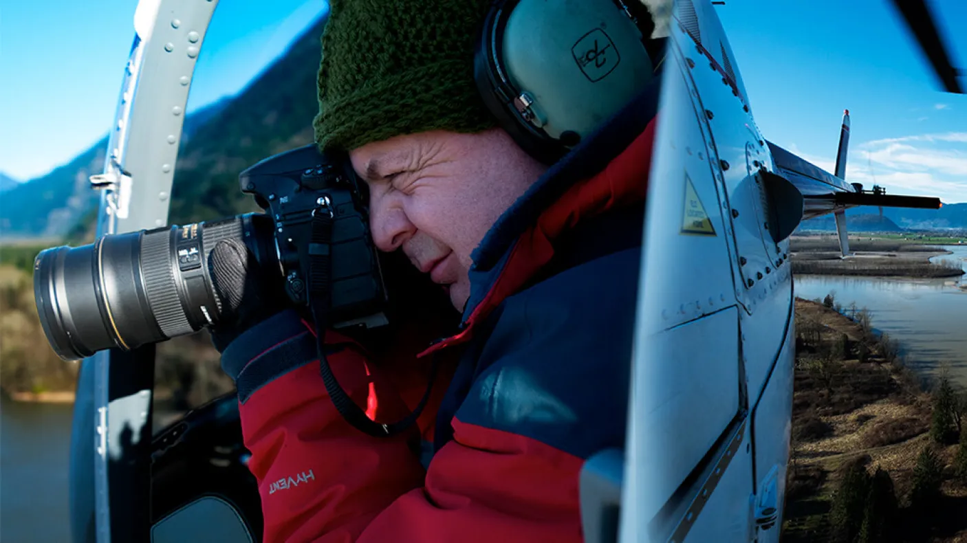 Andrew Wright taking a photograph in a helicopter.
