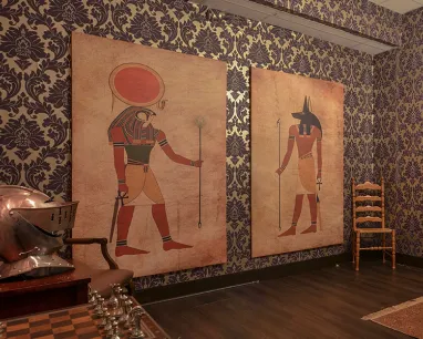 A mysterious looking room with two large prints of hieroglyphics on the wall.