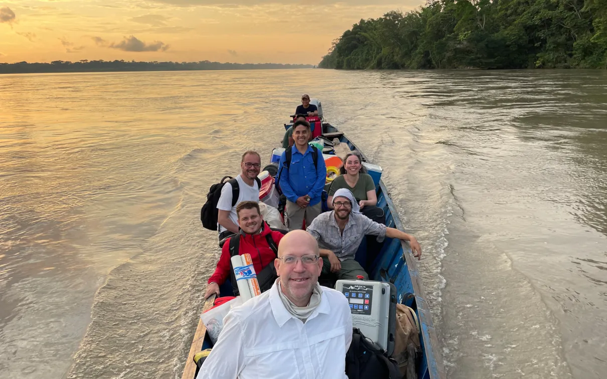 As the sun sets behind them, Dr. Nathan K. Lujan and his team boat down the Rio Napo, laden with an array of supplies.