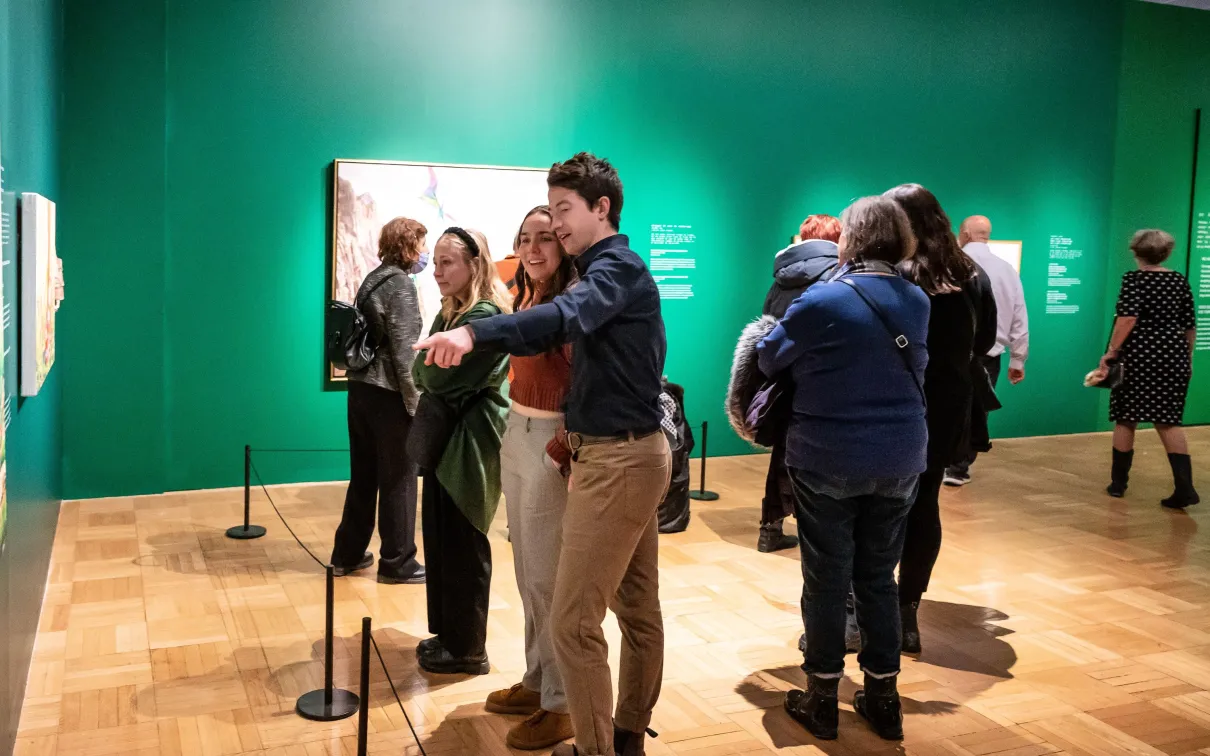 A young couple smile whiling looking at a picture the man is pointing at.