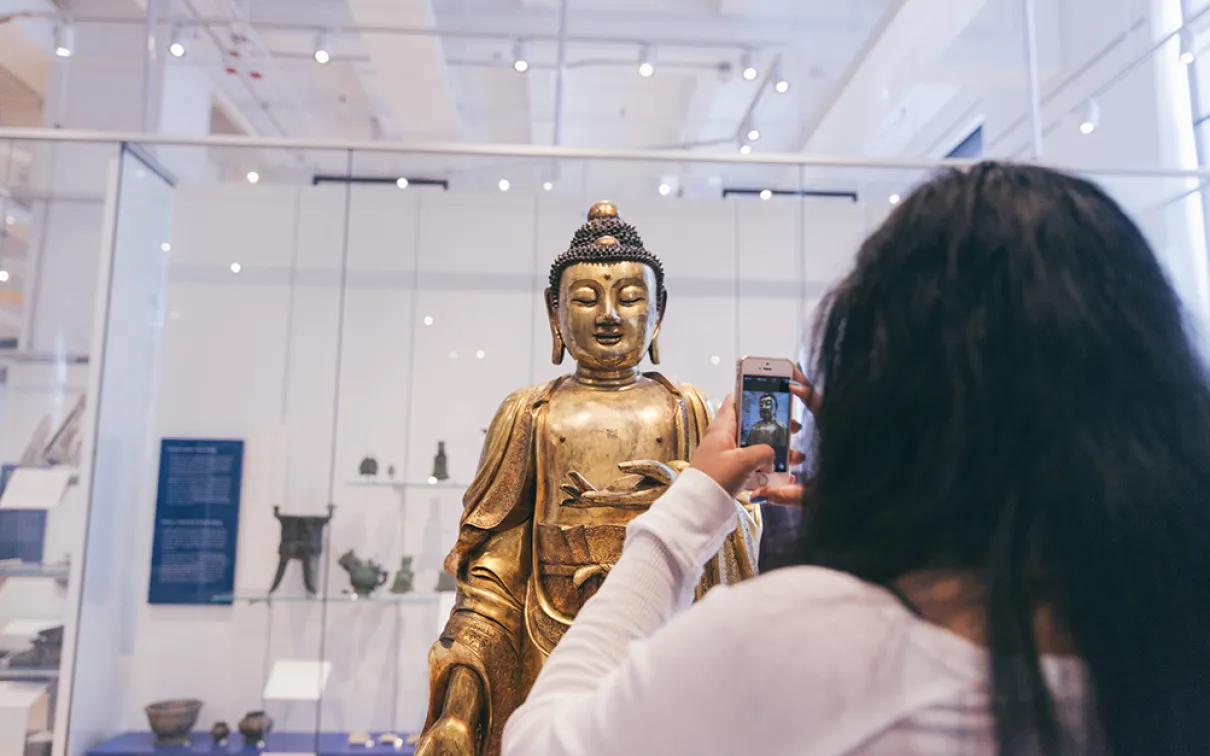 Person taking photo of statue in ROM gallery