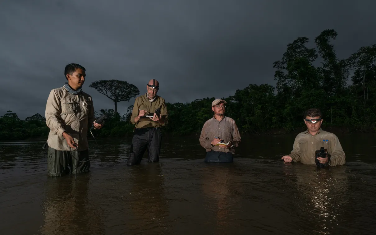 Four people standing knee-deep in water with equipment collecting data