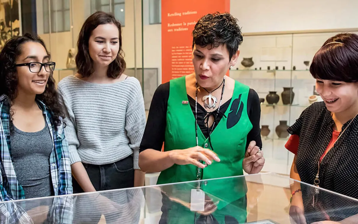 J’net AyAyQwaYakSheelth with students looking at a display case.
