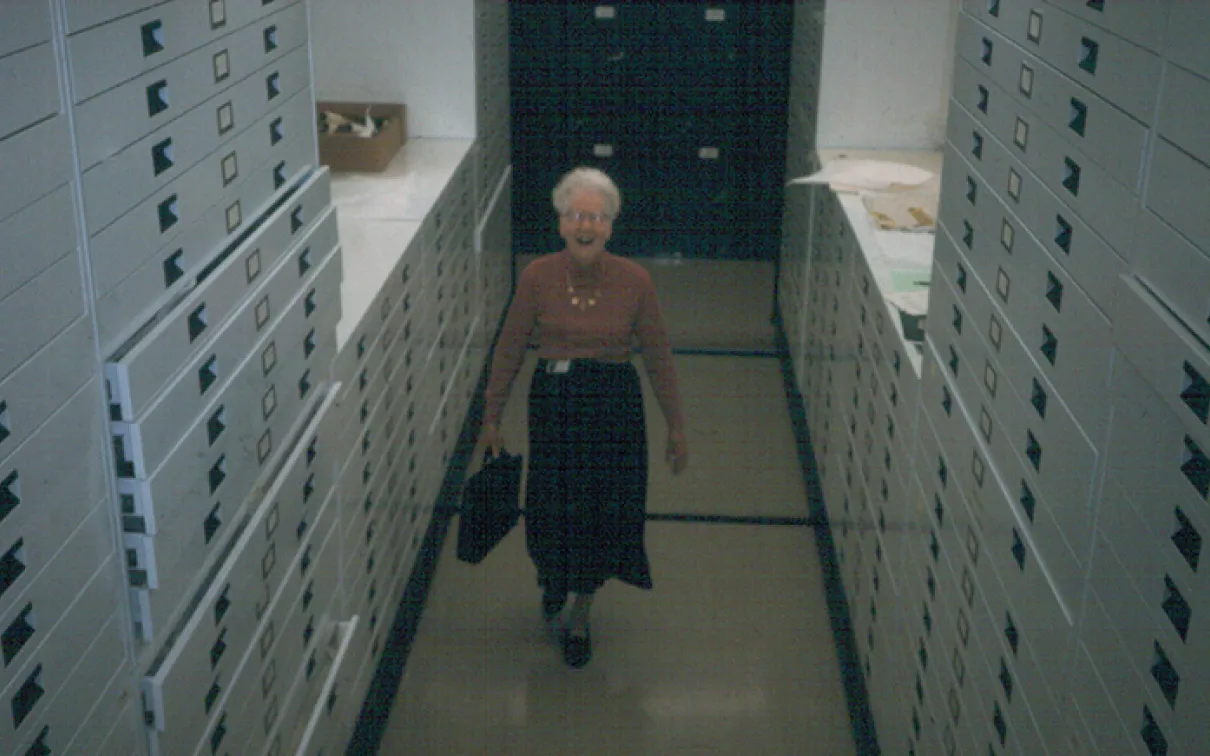 Photo of Dorothy Burnham standing in the textiles storage area.
