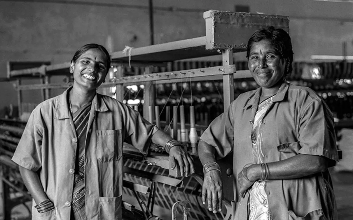 Two Indian craftspeople in front of textile manufacturing machine.