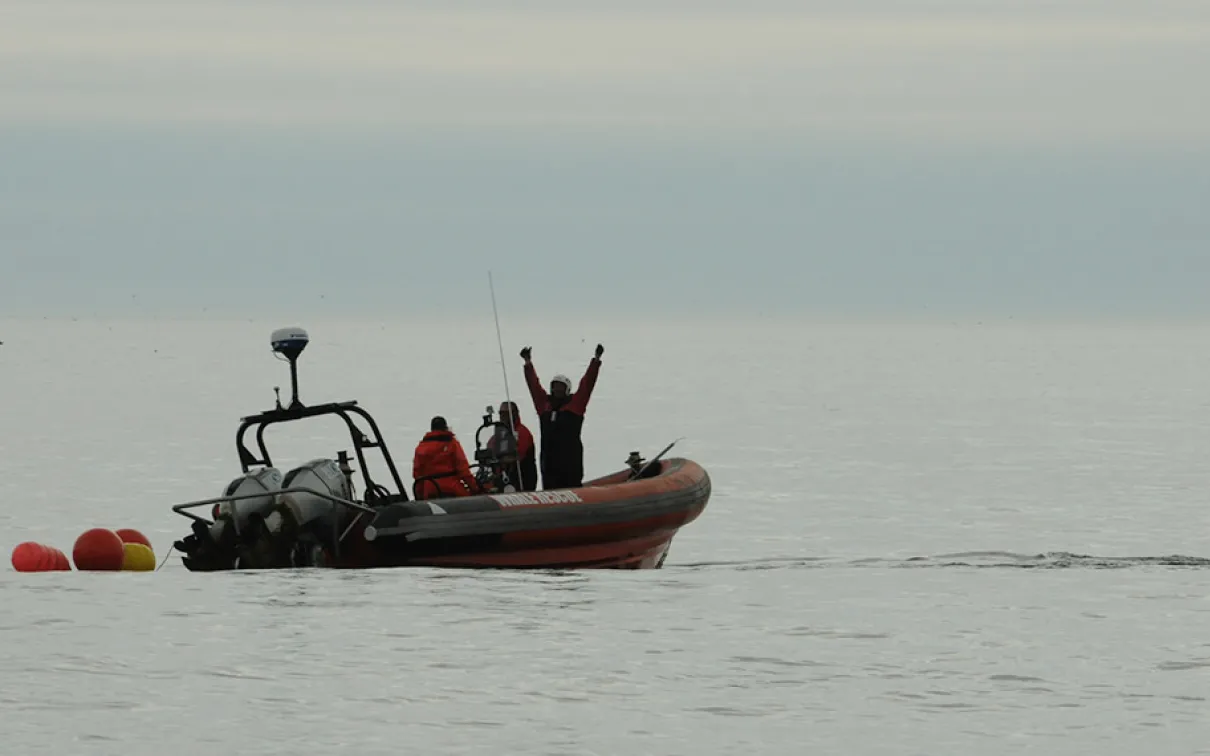 From the Great Whales, curator conversations, Zodiac boat on the ocean with researchers looking toward the photographer.