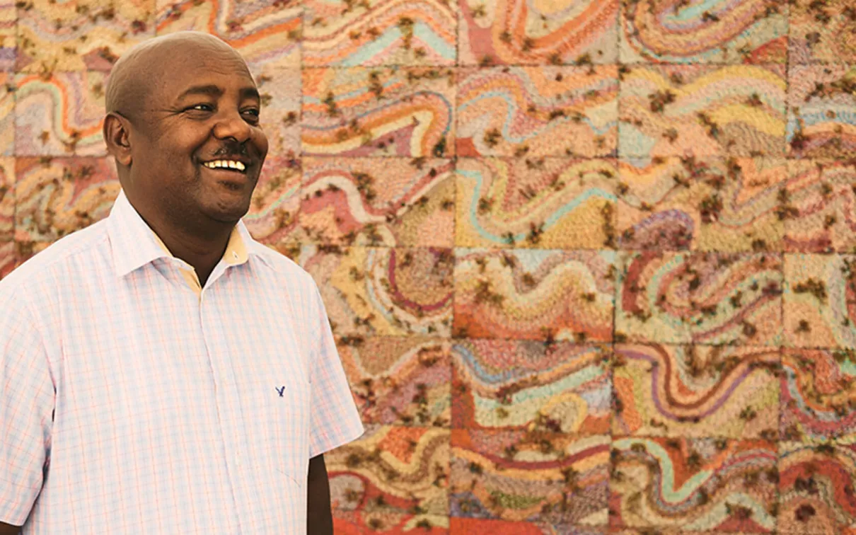 Elias Sime standing in front of his artwork.