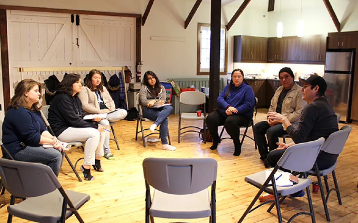 A group of Youth Cabinet members and facilitators sit in a circle with Tyler Pennock in 2017.
